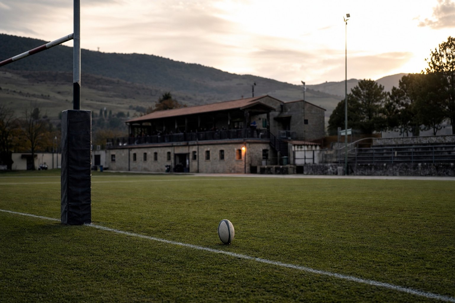 Campo di rugby di un club italiano al tramonto, con un pallone appoggiato sulla linea dei 22 metri
